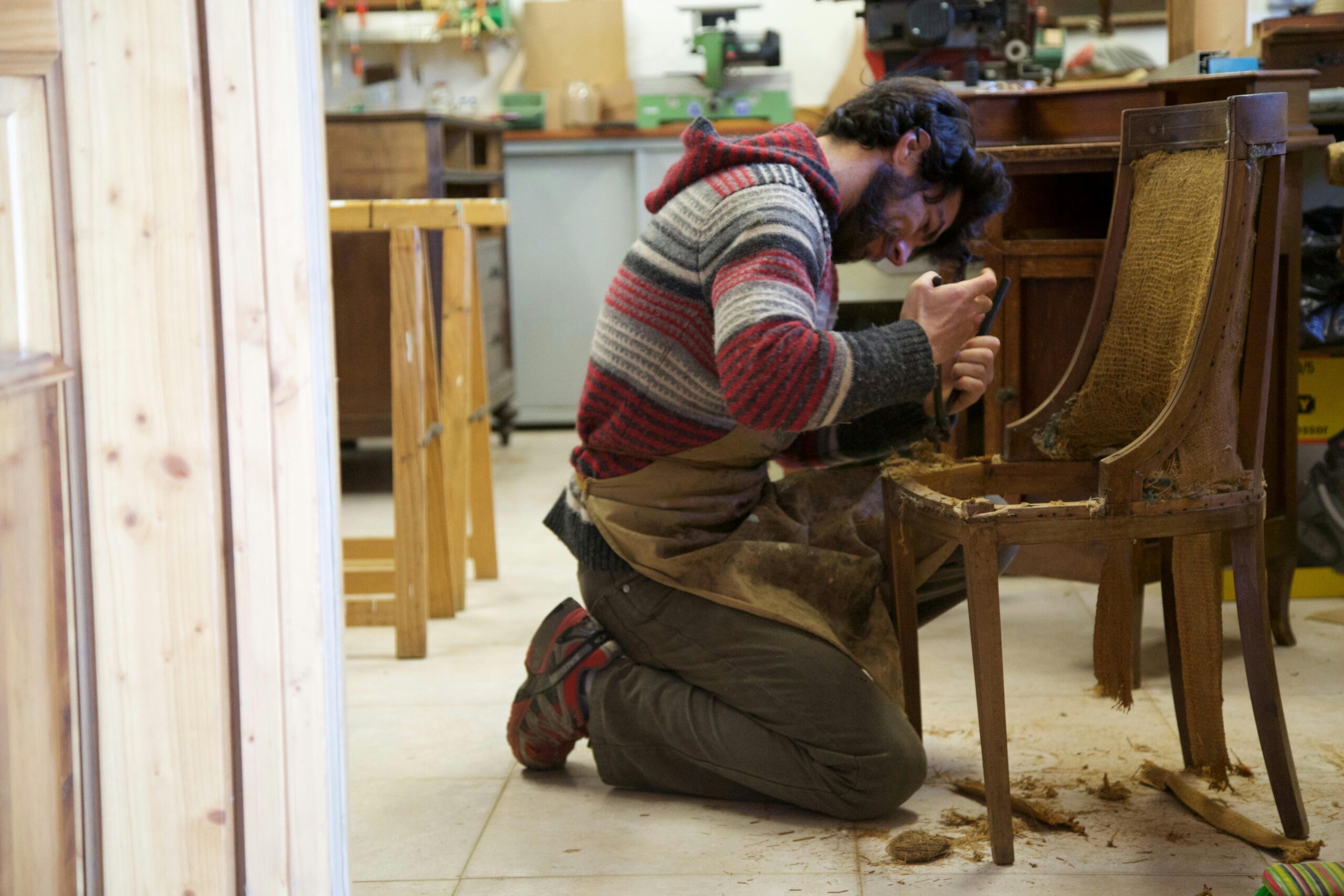 Skilled craftsman restoring an antique wooden chair in a workshop, focused on detailing.